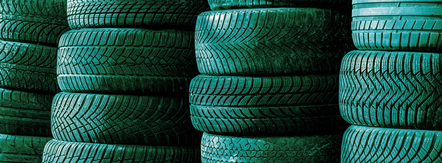 Neatly stacked passenger car tyres in emerald tones